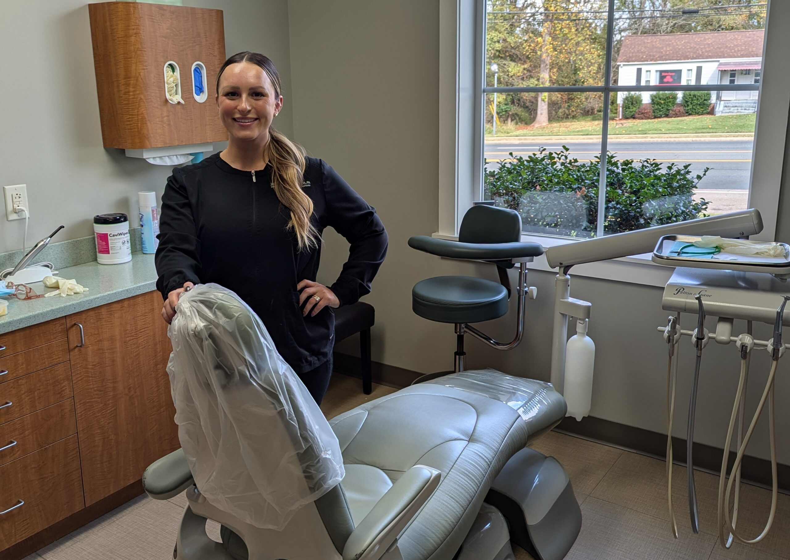 A dental hygienist standing by a dental chair